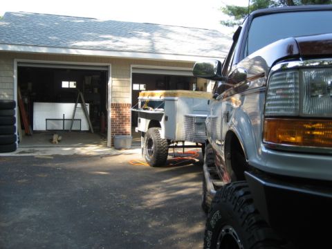 1996 Ford Bronco - A Ford F-Series truck is parked next to a trailer outside a garage.
