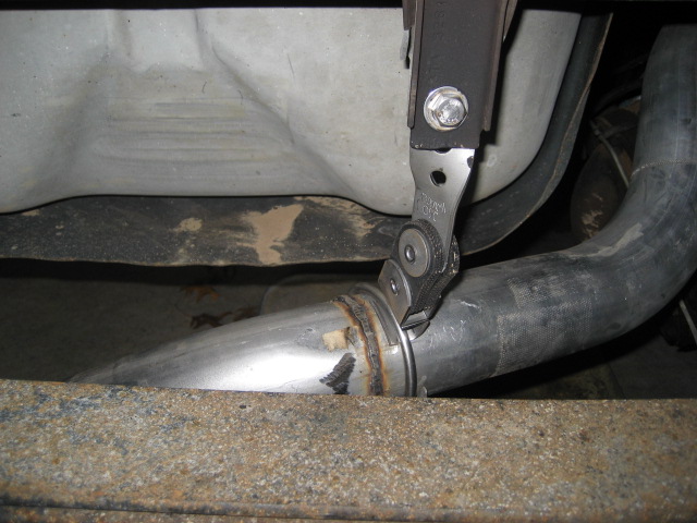 Exhaust pipe clamp securing a metal pipe to a vehicle frame