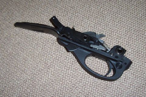 1994 Ford F-150 - A close-up view of a gun's trigger assembly, resting on a carpeted surface. The Supermotors.net logo is visible in the lower right corner.