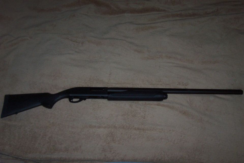 Black pump-action shotgun lying on a textured surface