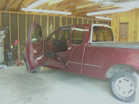 2007 Ford Mustang - A maroon pickup truck is parked inside a garage with its driver's door ajar.