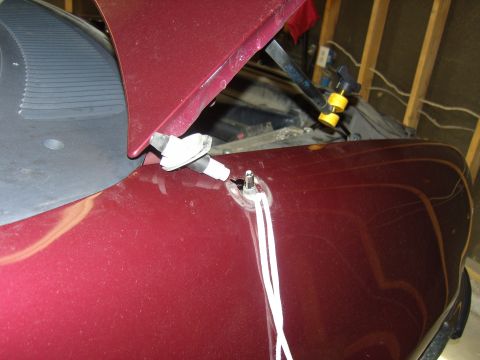 2007 Ford Mustang - Close-up of a windshield washer fluid nozzle and wiper assembly on the hood of a dark red vehicle.