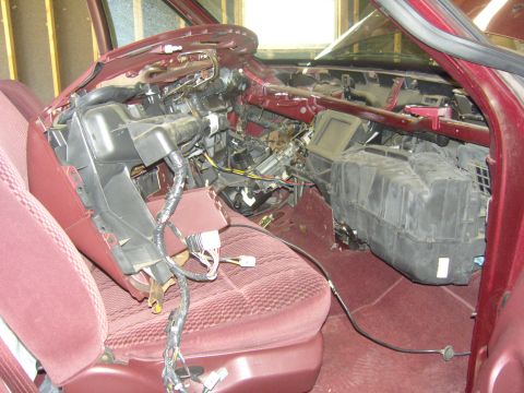 2007 Ford Mustang - Burgundy truck cab torn down for a heater-core job, with the dash pad removed to expose the steel dash bar, steering column, loose wiring h…