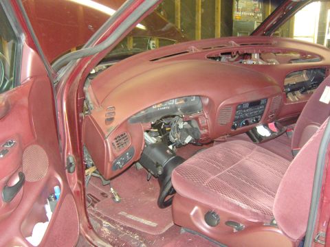 2007 Ford Mustang - Interior view of a burgundy/maroon truck cab with the dashboard partially disassembled, showing the exposed steering column, wiring, instru…