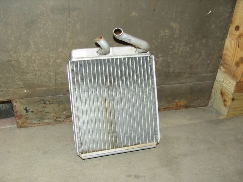 2007 Ford Mustang - A removed aluminum heater core standing on a concrete garage floor against a poured wall, with its two bent inlet/outlet tubes pointing up…