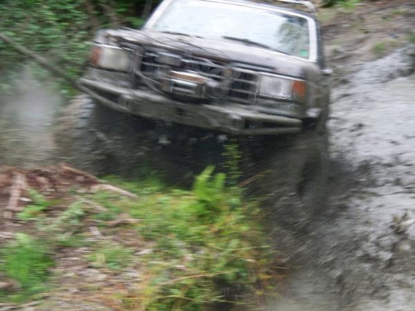 Ford Bronco driving through mud and water, splashing heavily