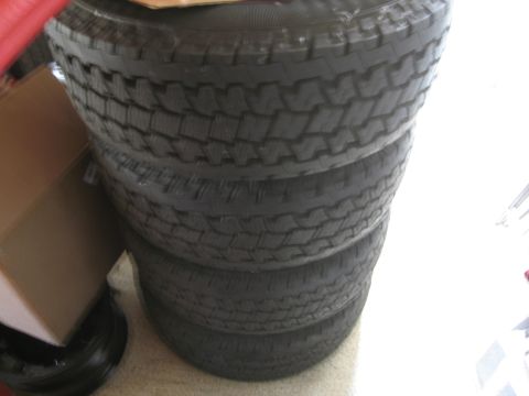 1986 Ford Bronco - Four tires are stacked on top of each other indoors.