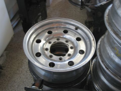 1986 Ford Bronco - Close-up of a single aluminum wheel, part of a stack of similar wheels.