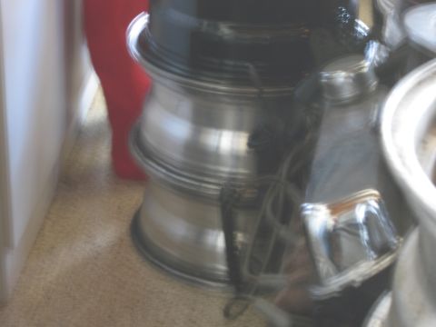 1986 Ford Bronco - Multiple aluminum alloy wheels are stacked indoors, with a red object and wall in the background.