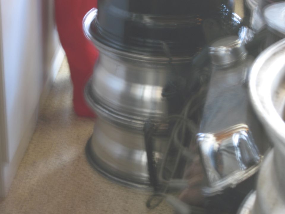 Stack of three aluminum alloy wheels with polished lips and dark centers, some showing wear