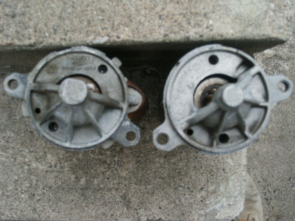 Two cast-aluminum pump housings with three-bolt mounting ears sitting on concrete