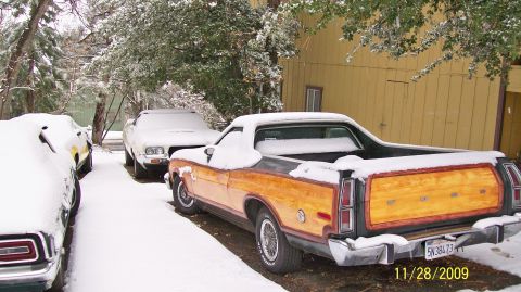 1973 Ford Ranchero - A 1973 Ford Ranchero with wood grain paneling is parked in the snow, with other vehicles nearby.