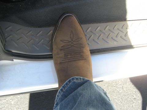2004 Ford F-150 - A cowboy boot is shown stepping onto the interior step plate of a truck.