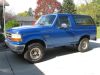 1992 Ford Bronco - A blue 1992 Ford Bronco is parked outside a house on a sunny day.