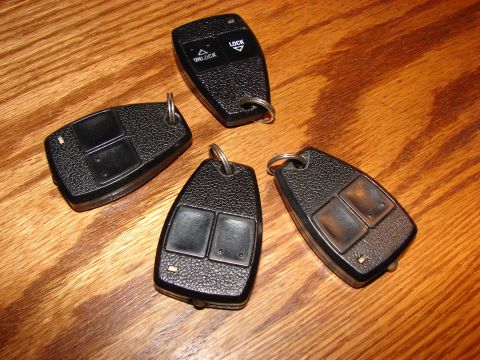 1996 Jeep Grand Cherokee - Four key fobs are displayed on a wooden surface. One fob shows labels for 'LOCK' and 'UNLOCK'.