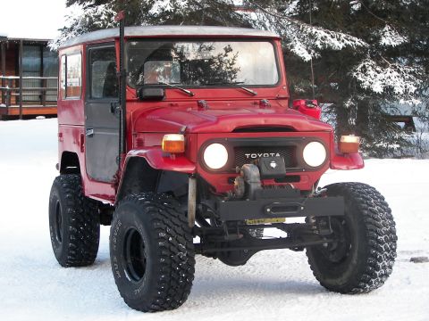 1990 Chevrolet Suburban - This red Toyota Land Cruiser FJ40 features a front-mounted winch and aggressive off-road tires, seen here in a snowy environment.