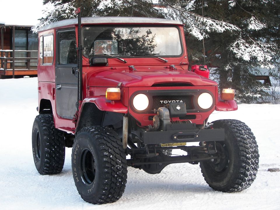 Red Toyota Land Cruiser FJ40 with winch and large tires in snow