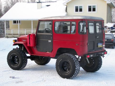 1990 Chevrolet Suburban - This red Toyota Land Cruiser FJ40 is equipped with large off-road tires and parked in a snowy environment.