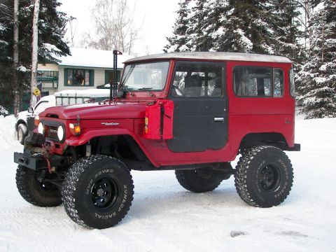 1990 Chevrolet Suburban - A red Toyota Land Cruiser FJ40 is parked in the snow with a white vehicle behind it.