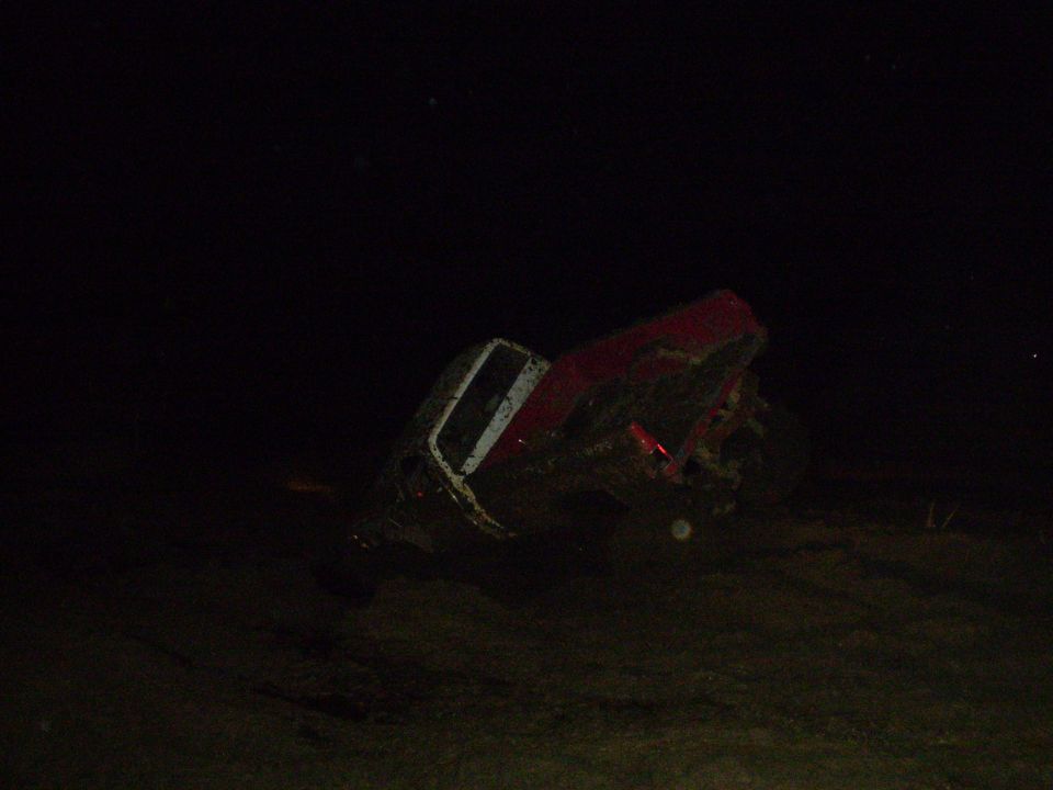 Muddy red pickup truck on its side