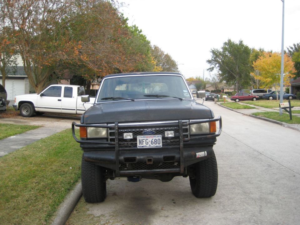 Black Ford Bronco with a brush guard and aftermarket bumper, parked on a residential street