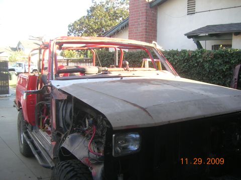 1985 Ford Bronco - This heavily modified Ford Bronco shows significant damage and missing body panels, indicating it is undergoing extensive repairs.