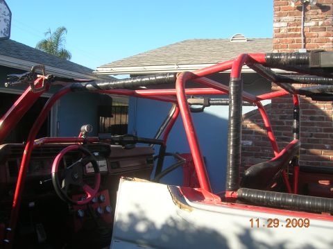 1985 Ford Bronco - The interior of a custom-built buggy shows a red roll cage and a modified dashboard with multiple gauges.