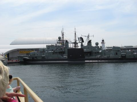 2008 Ford F-250 - A fleet of naval vessels, including a submarine, are docked at a harbor next to a building and a lighthouse.