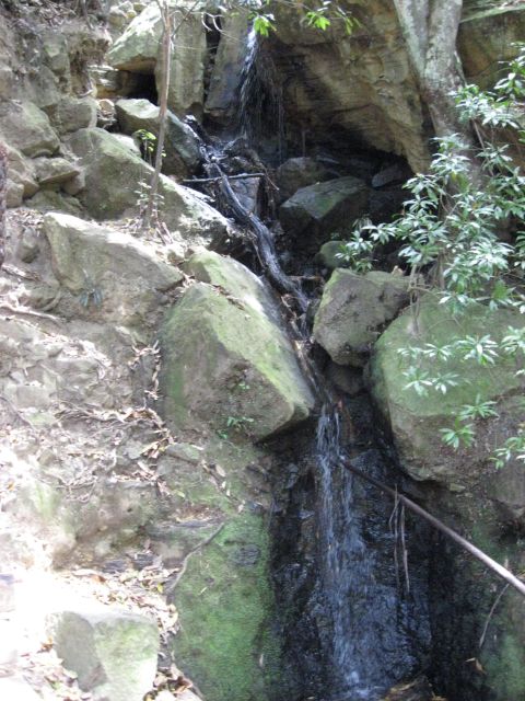2008 Ford F-250 - A natural waterfall flows down a rocky incline, surrounded by trees and vegetation.