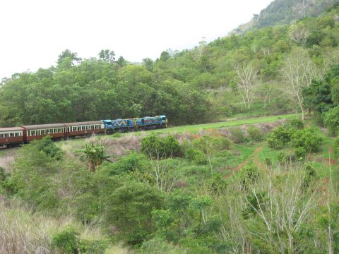 2008 Ford F-250 - A train travels along a track through a lush, green landscape with a hill in the background.
