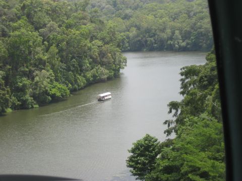 2008 Ford F-250 - A houseboat travels down a calm river, bordered by dense, green trees on both sides.