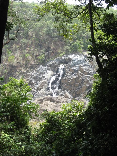 2008 Ford F-250 - A scenic view of a waterfall flowing over a rock face, framed by dense forest vegetation.