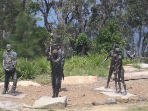 2008 Ford F-250 - Several bronze statues depicting human figures are displayed in an outdoor park-like setting.