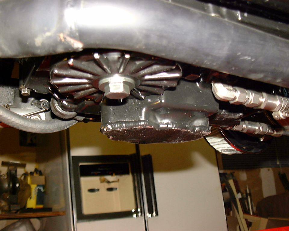 Underside of motorcycle engine showing welded extended oil pan and braided lines