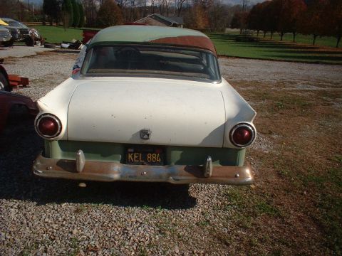 1957 Ford Custom Sedan - The rear of a vintage two-tone sedan, showing its distinctive tail fins and round taillights.