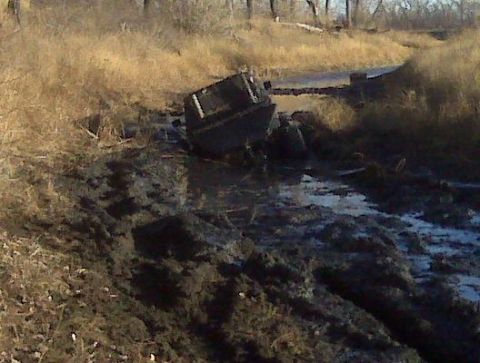 1992 Ford F-350 - A truck is stuck in a muddy, watery ditch surrounded by dry grass and trees.