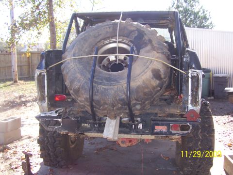 1978 Ford Bronco - A large spare tire is secured to the rear of a heavily modified off-road vehicle.