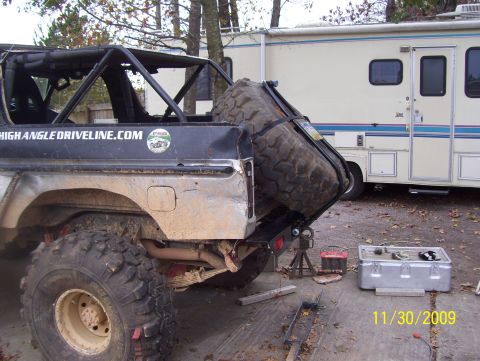 1978 Ford Bronco - Spare tire carrier mounted on the rear of an off-road vehicle, with an RV in the background.