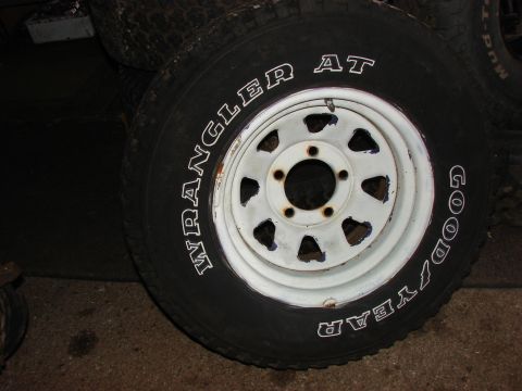 1984 Ford F-250 - A close-up of a Goodyear Wrangler AT tire mounted on a white rim, with other tires visible in the background.