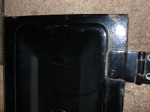 1984 Ford F-250 - Close-up of a black metal panel showing a hinge and some surface wear.
