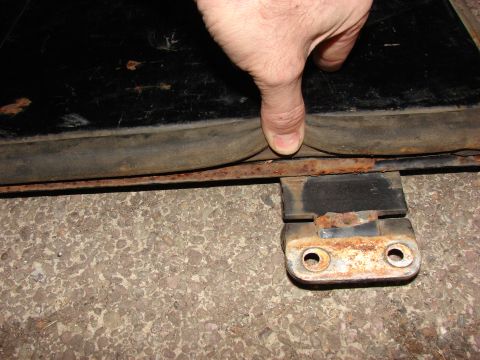 1984 Ford F-250 - Close-up of a rubber seal and rusty metal bracket on concrete, with a logo at the bottom right.
