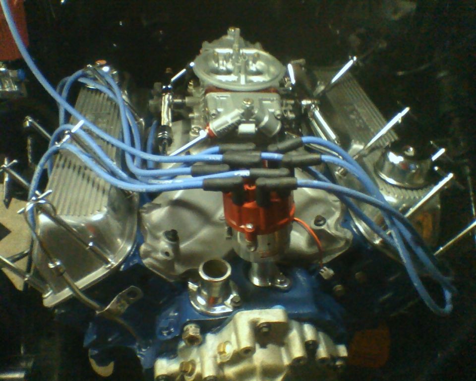 Ford V8 engine with blue spark plug wires, red distributor cap, and chrome valve covers