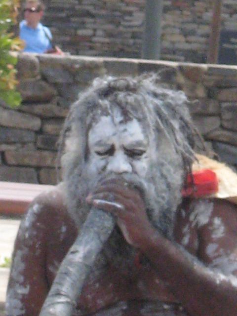 2008 Ford F-250 - A person playing a didgeridoo, with a stone wall and another person in the background.