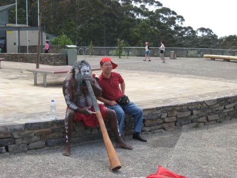 2008 Ford F-250 - A tourist watches an Aboriginal man perform with a didgeridoo at an outdoor cultural site.