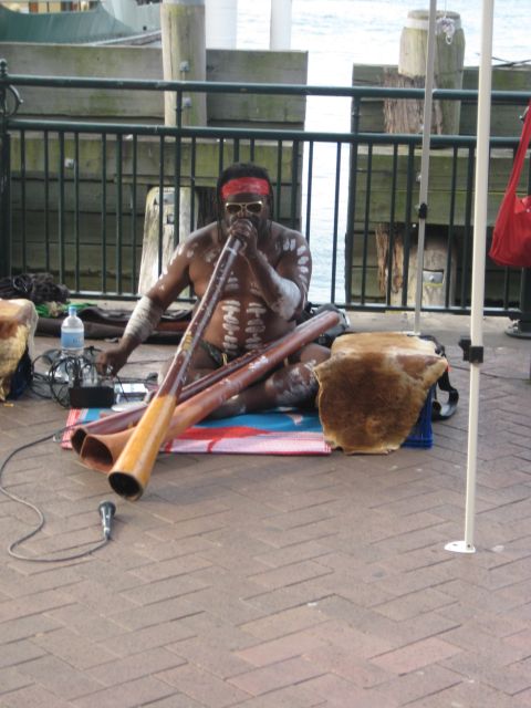 2008 Ford F-250 - A man in traditional body paint plays a didgeridoo outdoors, with a microphone and cables nearby.