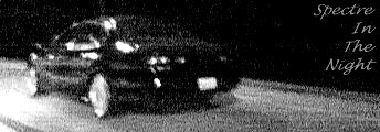 1999 Ford Taurus - A black sedan is captured in motion at night, its headlights illuminating the road ahead.
