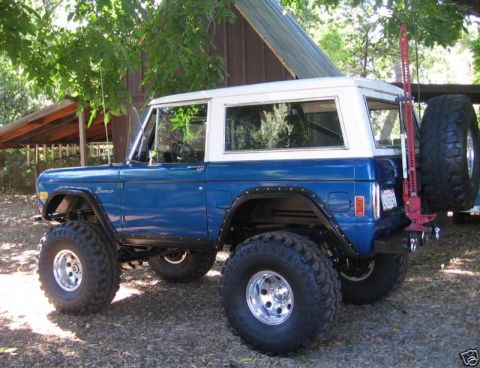 1977 Ford Bronco - A blue and white 1977 Ford Bronco is shown with a lifted suspension and off-road tires.