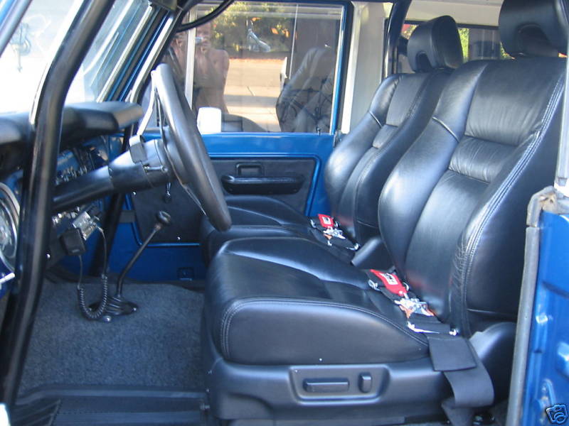 Black leather seats with red harnesses in a blue-trimmed Bronco interior