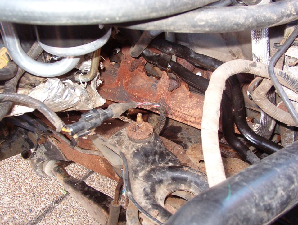 Rusty engine and frame area viewed from underneath a vehicle
