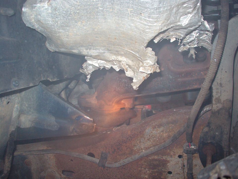 Glowing exhaust manifold under torn heat shield insulation